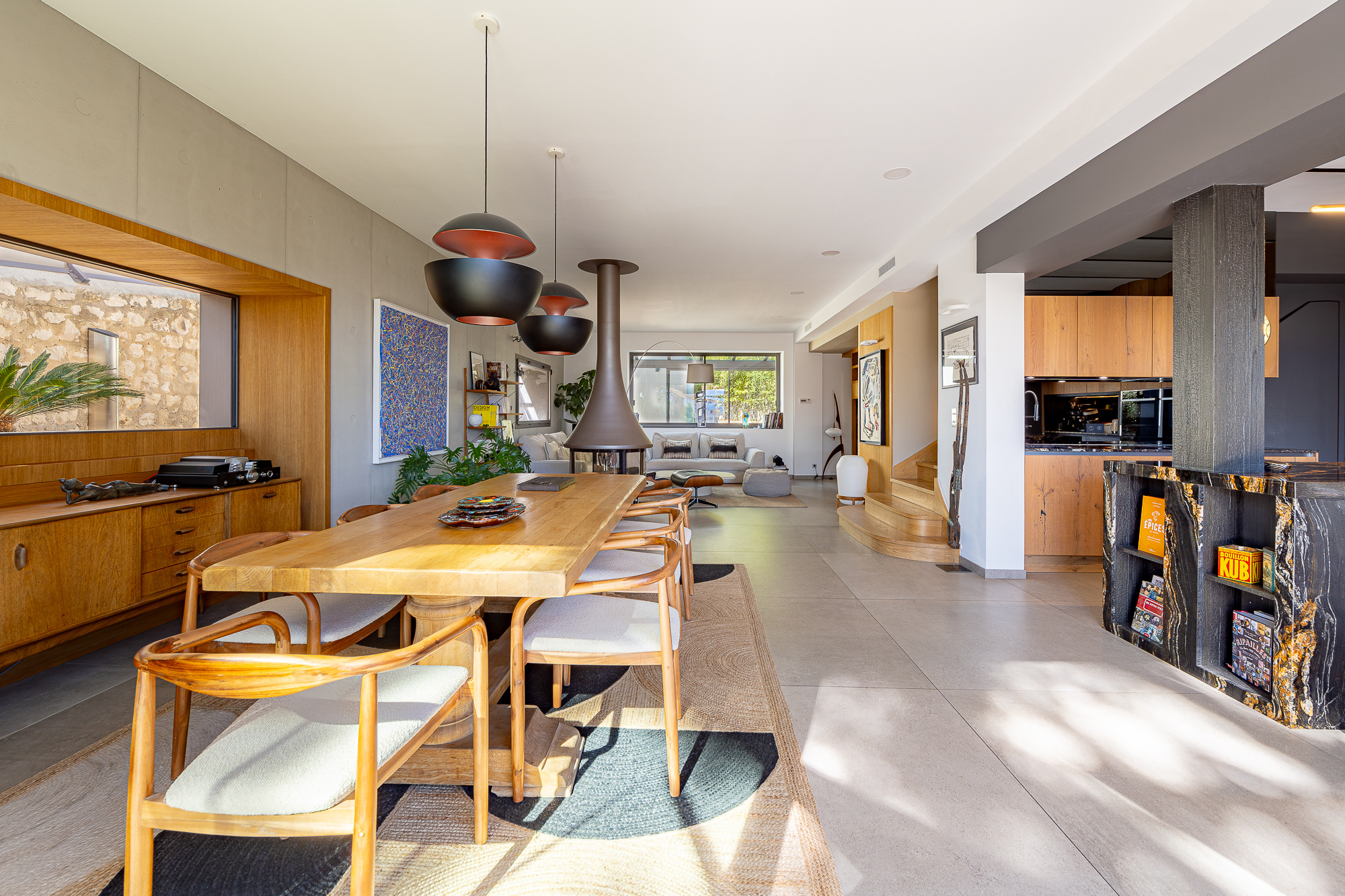 Intérieur d'une maison rénovée avec salle à manger, cuisine moderne et cheminée.