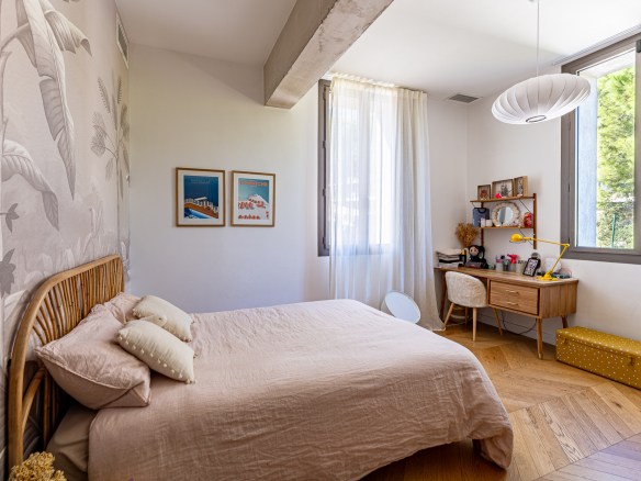 Chambre d'une maison rénovée avec un lit, un bureau et des fenêtres lumineuses.