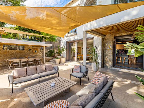 Terrasse d'une maison rénovée avec salon extérieur et parasols à Marseille.
