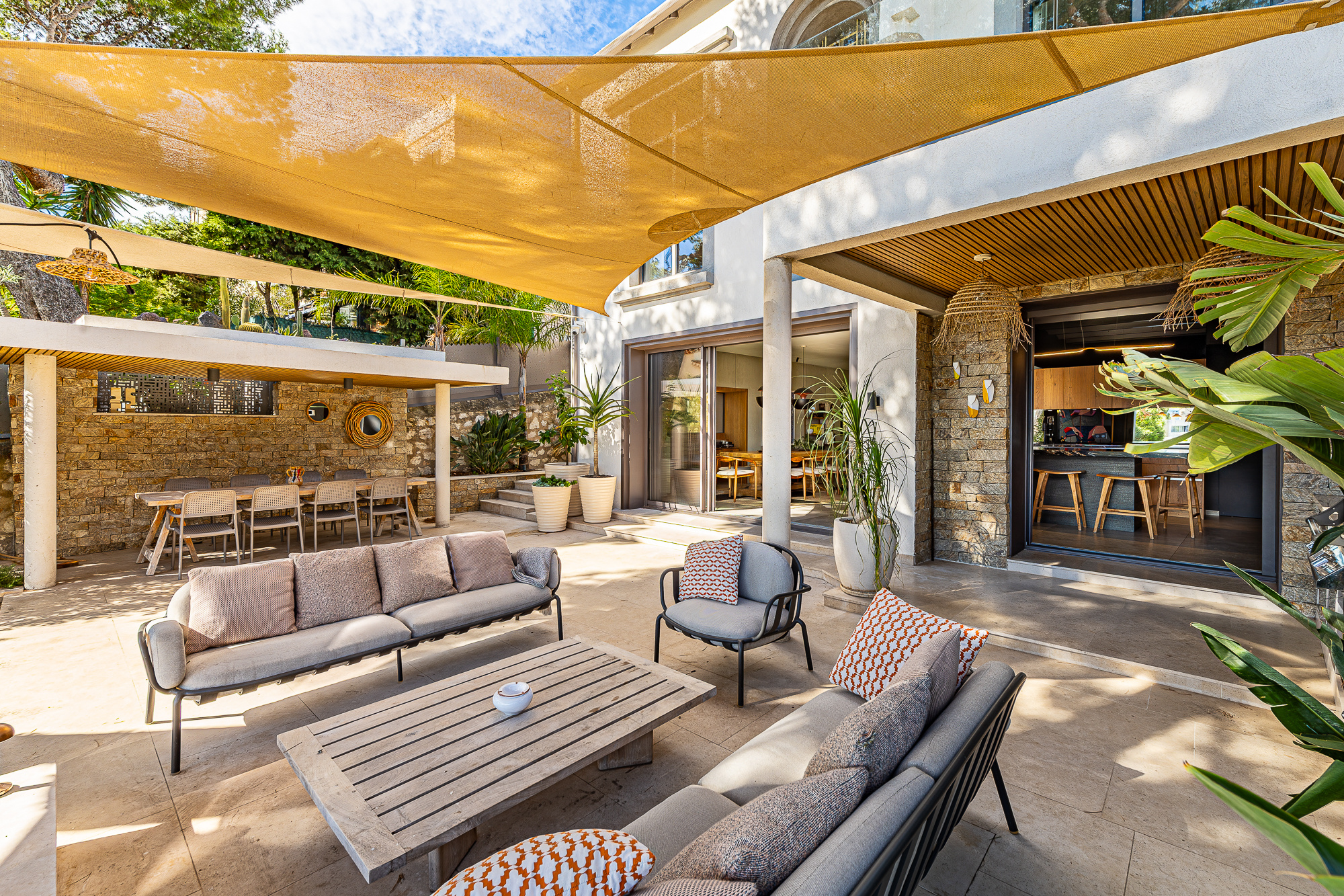Terrasse d'une maison rénovée avec salon extérieur et parasols à Marseille.