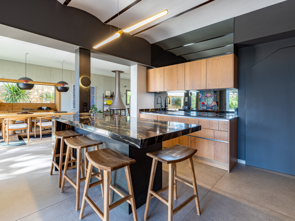 Cuisine moderne avec îlot central et bar, éclairage design, ouverte sur salle à manger.