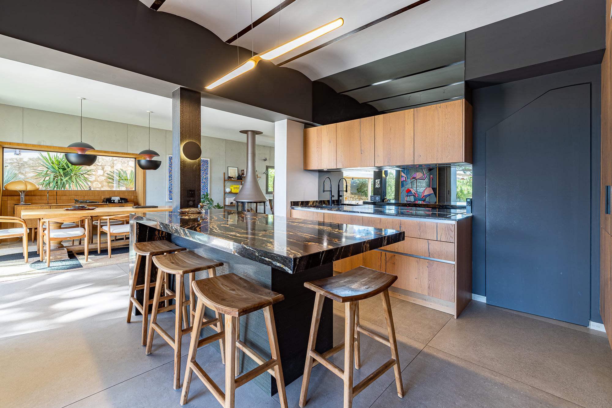 Cuisine moderne avec îlot central et bar, éclairage design, ouverte sur salle à manger.