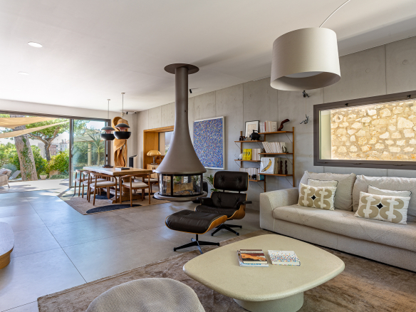 Intérieur d'une maison rénovée avec salon, cheminée moderne et vue sur jardin.