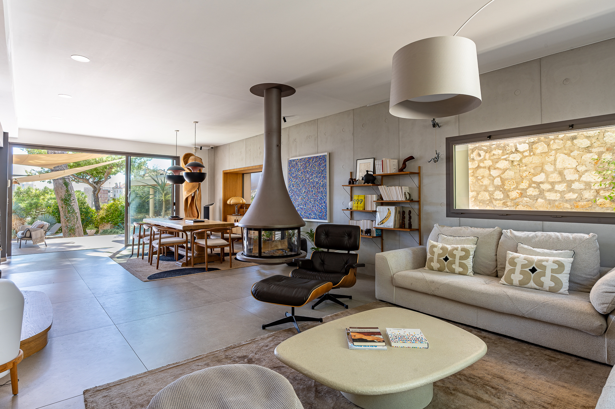Intérieur d'une maison rénovée avec salon, cheminée moderne et vue sur jardin.