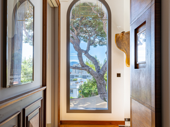 Intérieur d'une maison rénovée avec un grand vitrage et un arbre visible à l'extérieur.