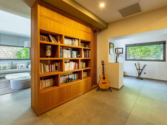 Intérieur d'une maison rénovée avec bibliothèque en bois et guitare, Marseille.
