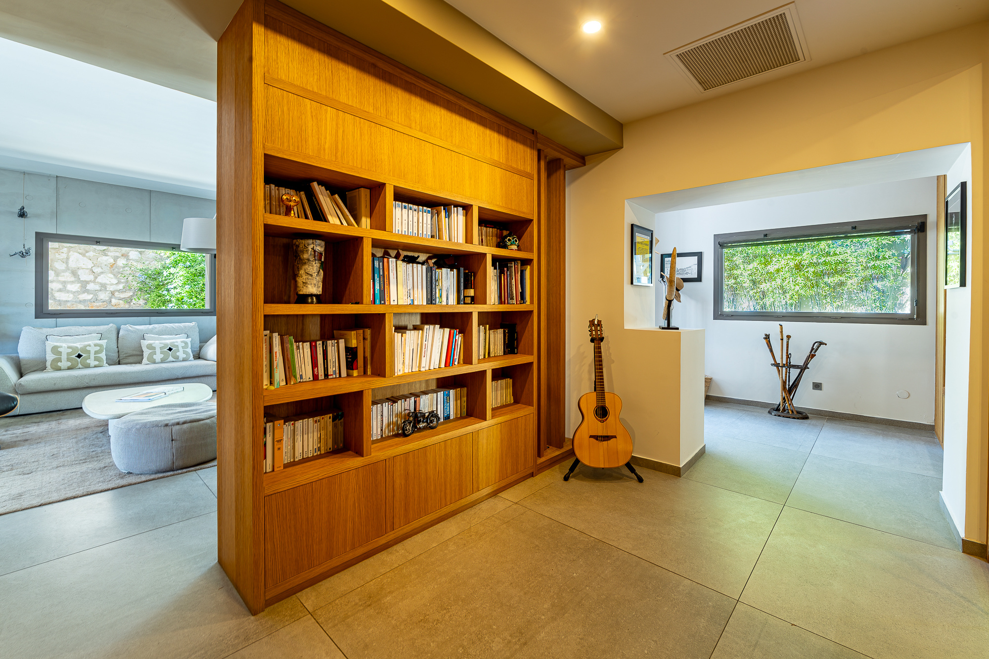 Intérieur d'une maison rénovée avec bibliothèque en bois et guitare, Marseille.