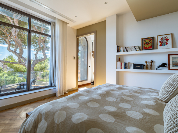 Chambre lumineuse avec fenêtre sur jardin, décoration contemporaine et literie à pois.