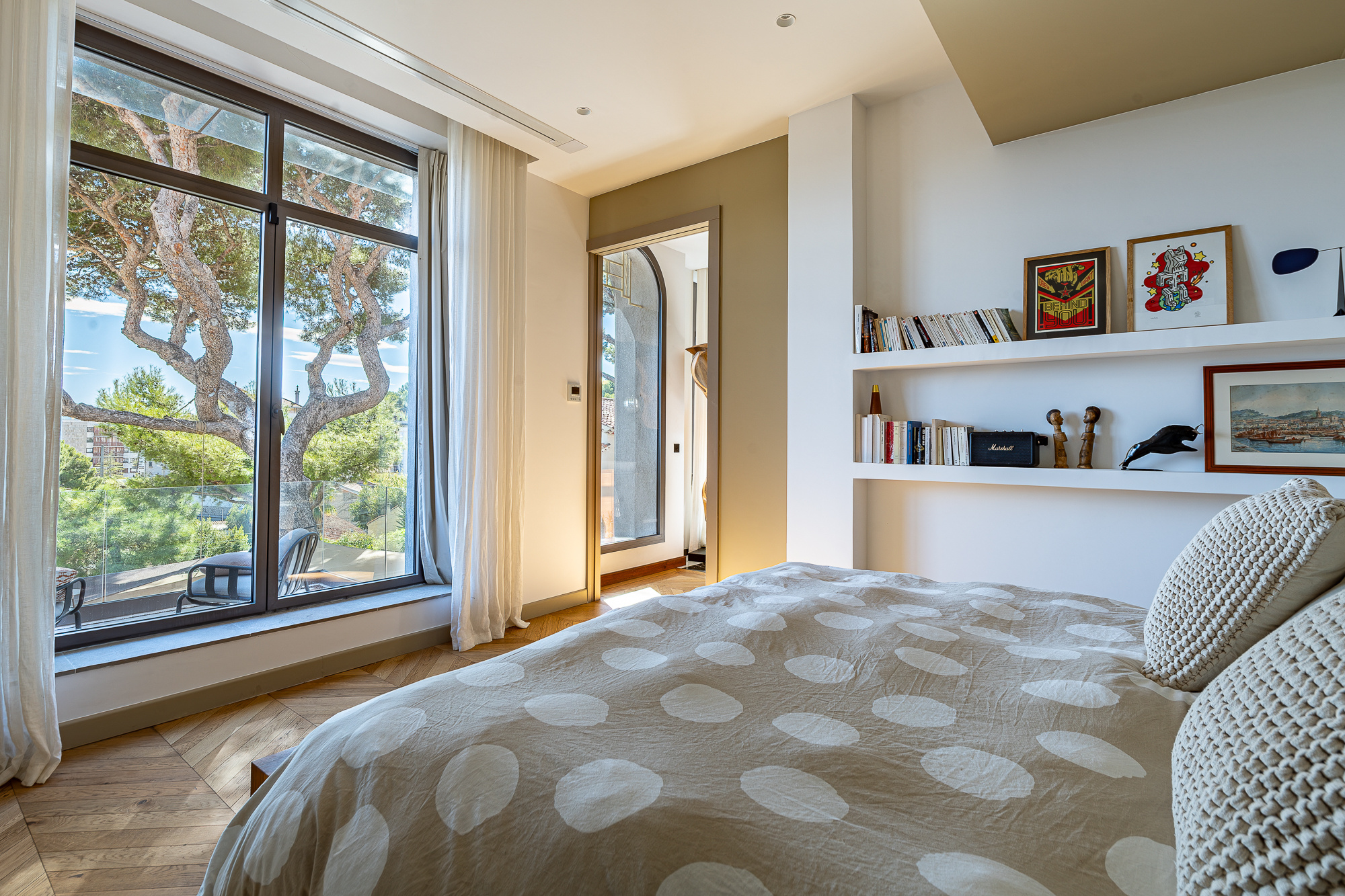 Chambre lumineuse avec fenêtre sur jardin, décoration contemporaine et literie à pois.