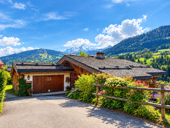 Traditional wooden chalet with flower garden, located in Megève, surrounded by mountains.