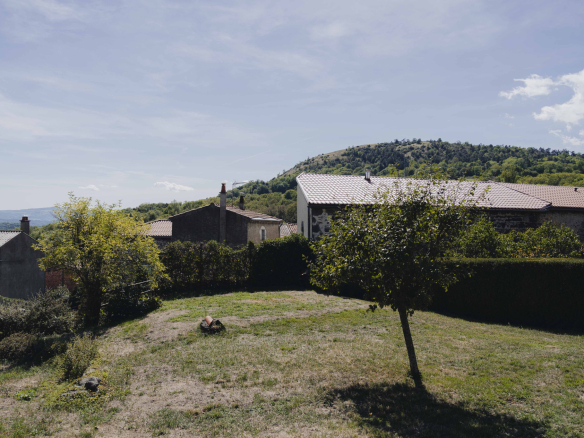 View of a renovated old farmhouse with a garden and mountains in the background in Olloix.