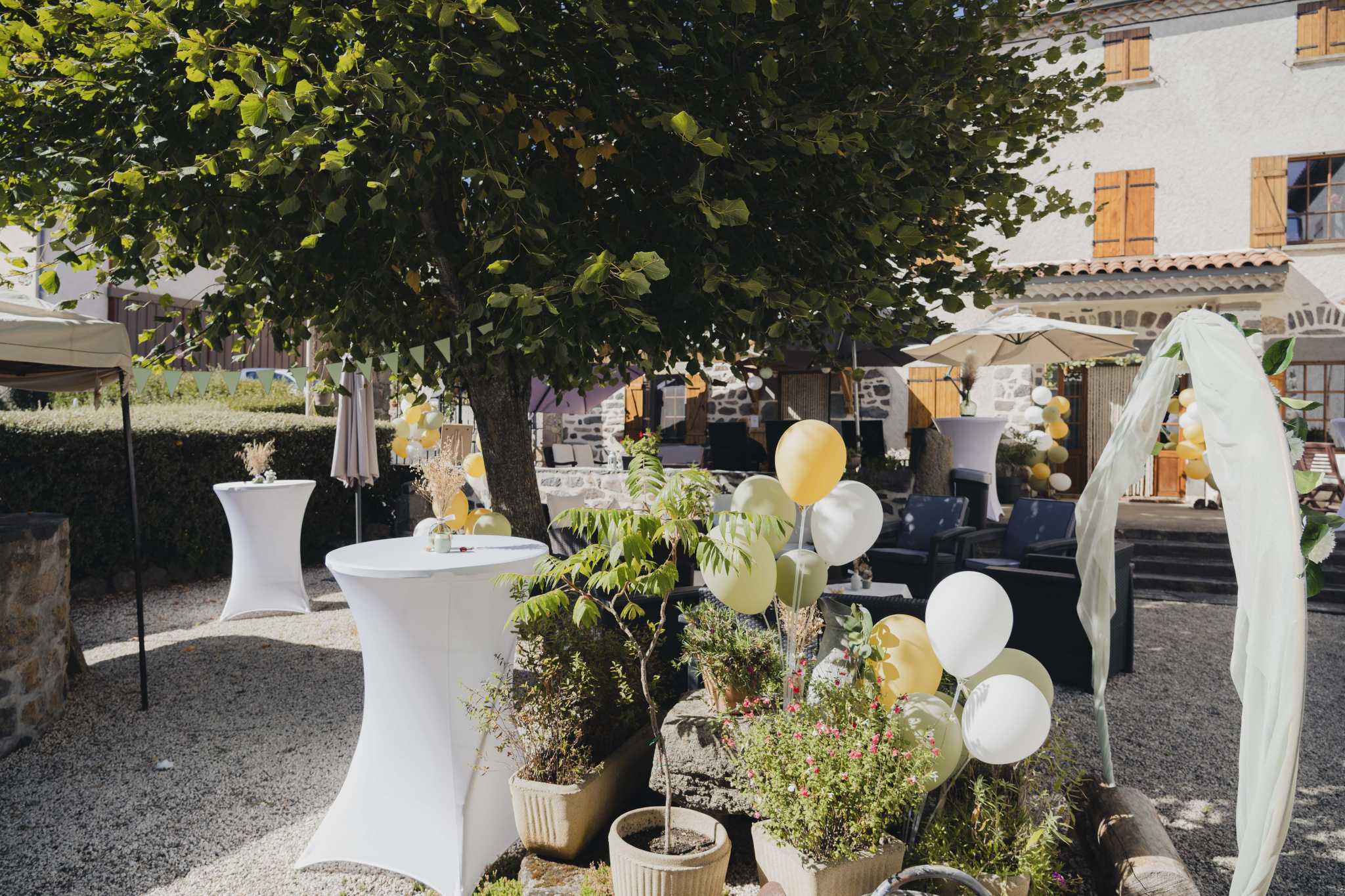 Terrace of a renovated old farmhouse with tables and chairs, decorated with balloons, in Olloix.