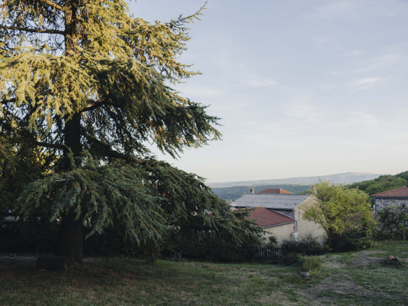 View of a renovated old farmhouse with a tree and the mountains in the background in Olloix.