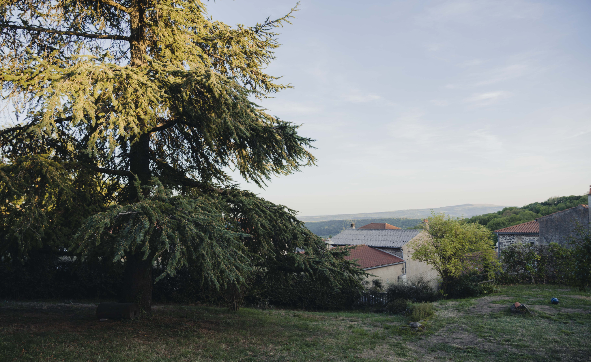 View of a renovated old farmhouse with a tree and the mountains in the background in Olloix.