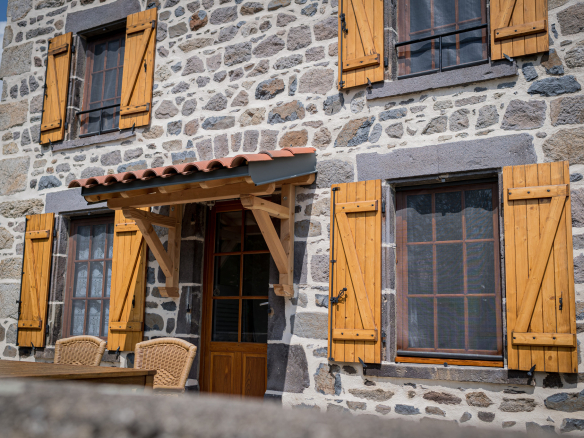 Facade of a renovated old Auvergne farmhouse with wooden shutters in Olloix.