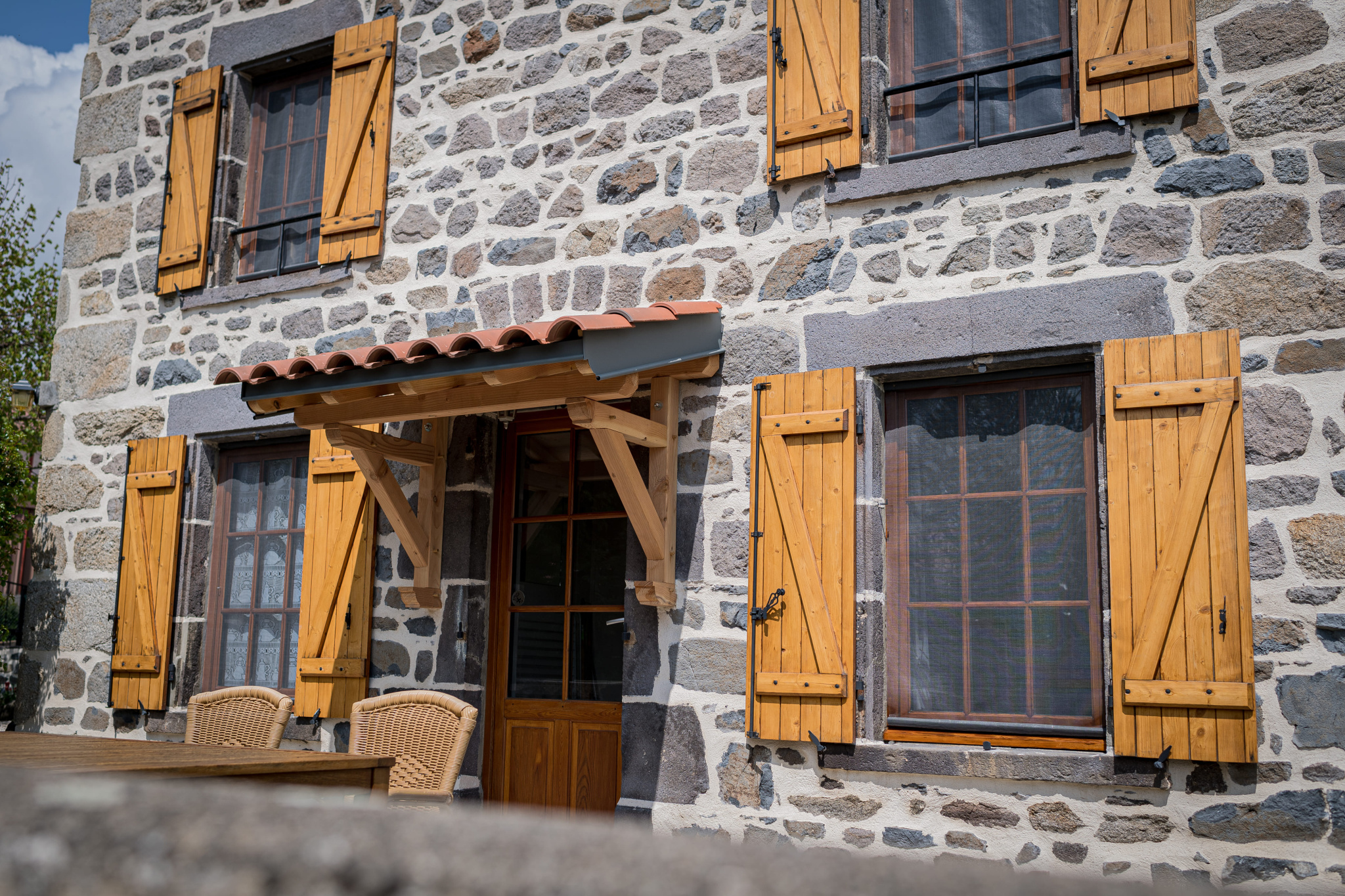 Facade of a renovated old Auvergne farmhouse with wooden shutters in Olloix.