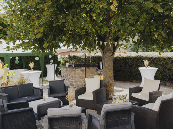 Terrace furnished with armchairs and tables around a tree, in a natural setting in Olloix.