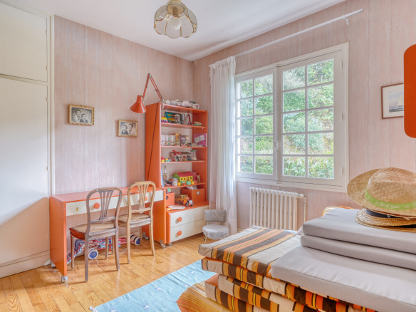 Room in a house to be renovated with orange furniture and a window overlooking the outside.