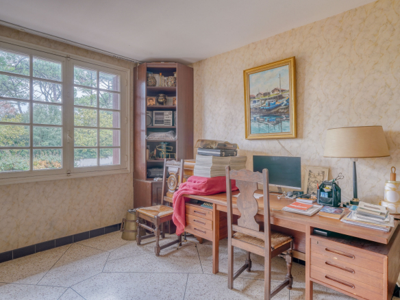 Office with wooden furniture and a window overlooking the outside in a house to be renovated.
