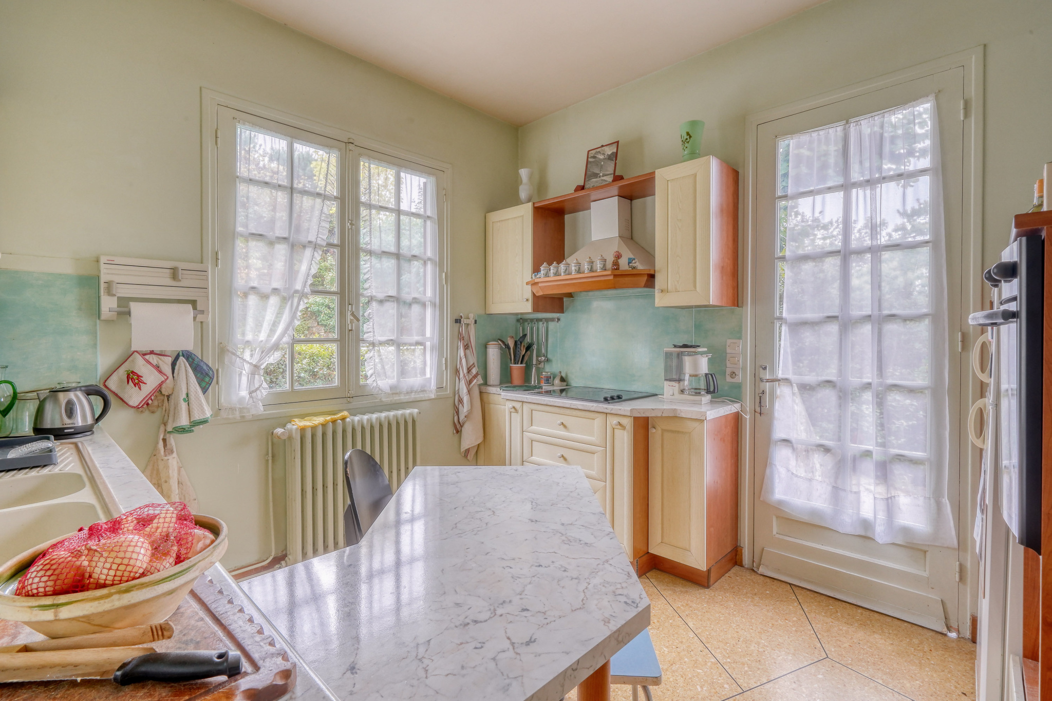 Kitchen in a house to be renovated in La Teste-de-Buch Kitchen of a traditional house with light-colored furniture and windows overlooking the outside.