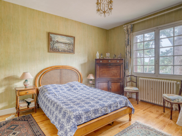 Bedroom in a traditional house with bed, wooden furniture and window overlooking the outside.