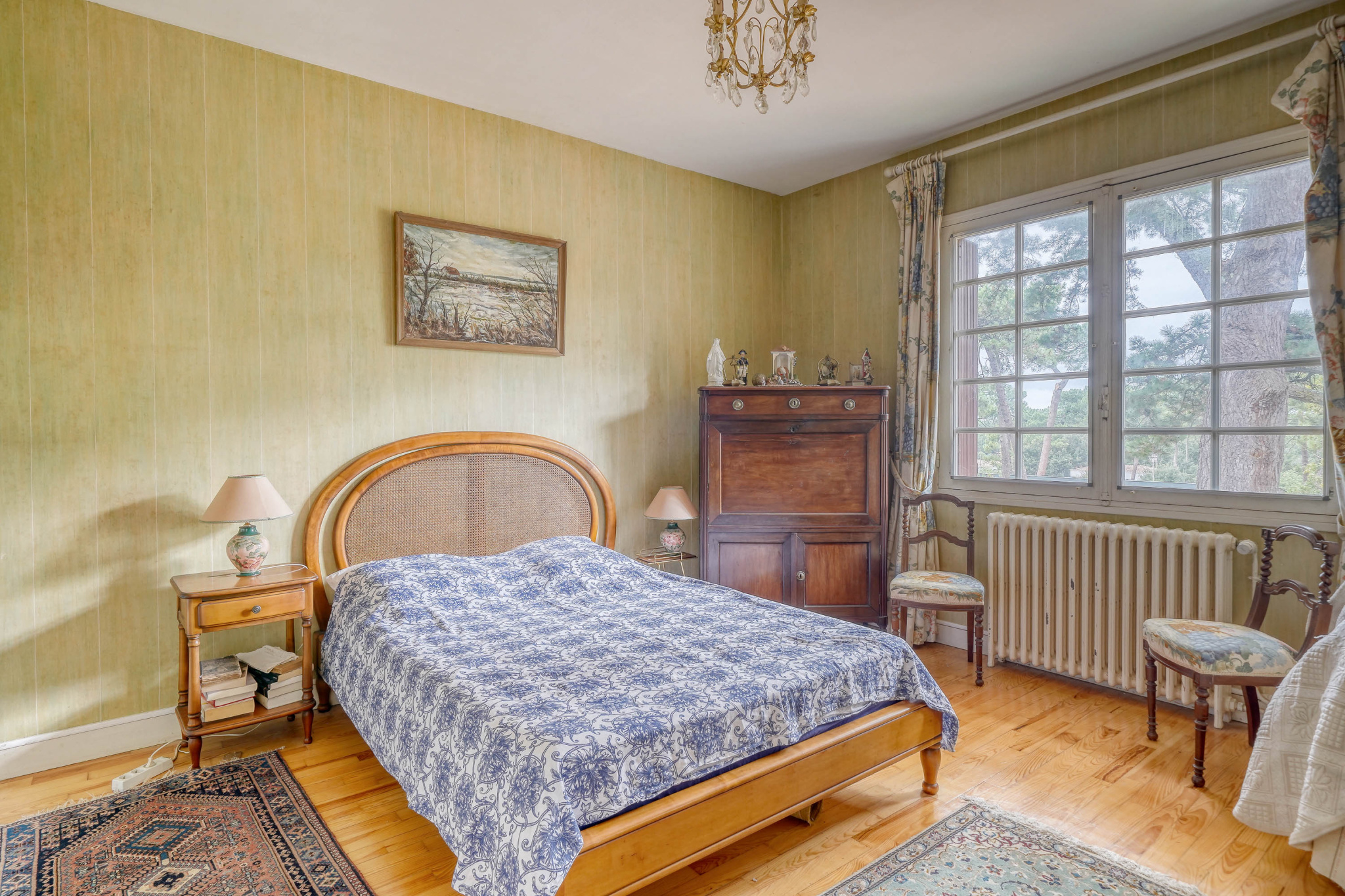 Room in a house in need of renovation Bedroom in a traditional house with bed, wooden furniture and window overlooking the outside.