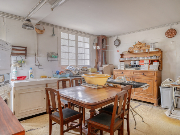 Kitchen of a traditional house to be renovated, with wooden table and visible equipment.