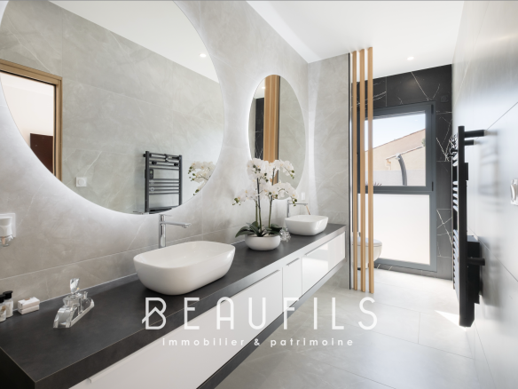 Modern bathroom with double sink and large windows.