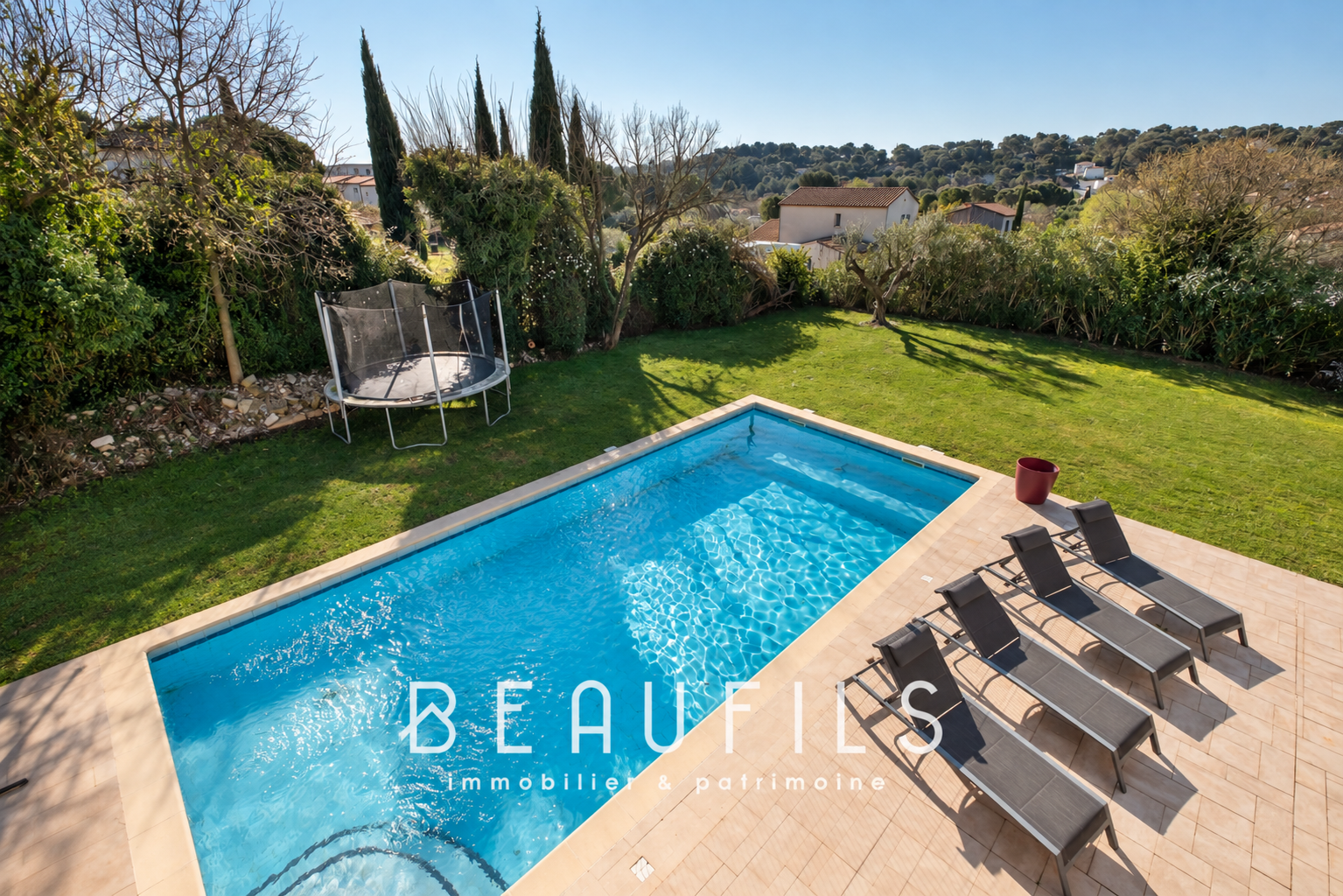 Architect-designed villa with swimming pool in Nîmes View of a villa with swimming pool and sun loungers, green garden in the background.
