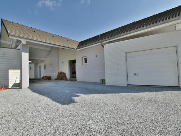 Vue de l'extérieur d'une maison moderne avec garage et allée en gravier.
