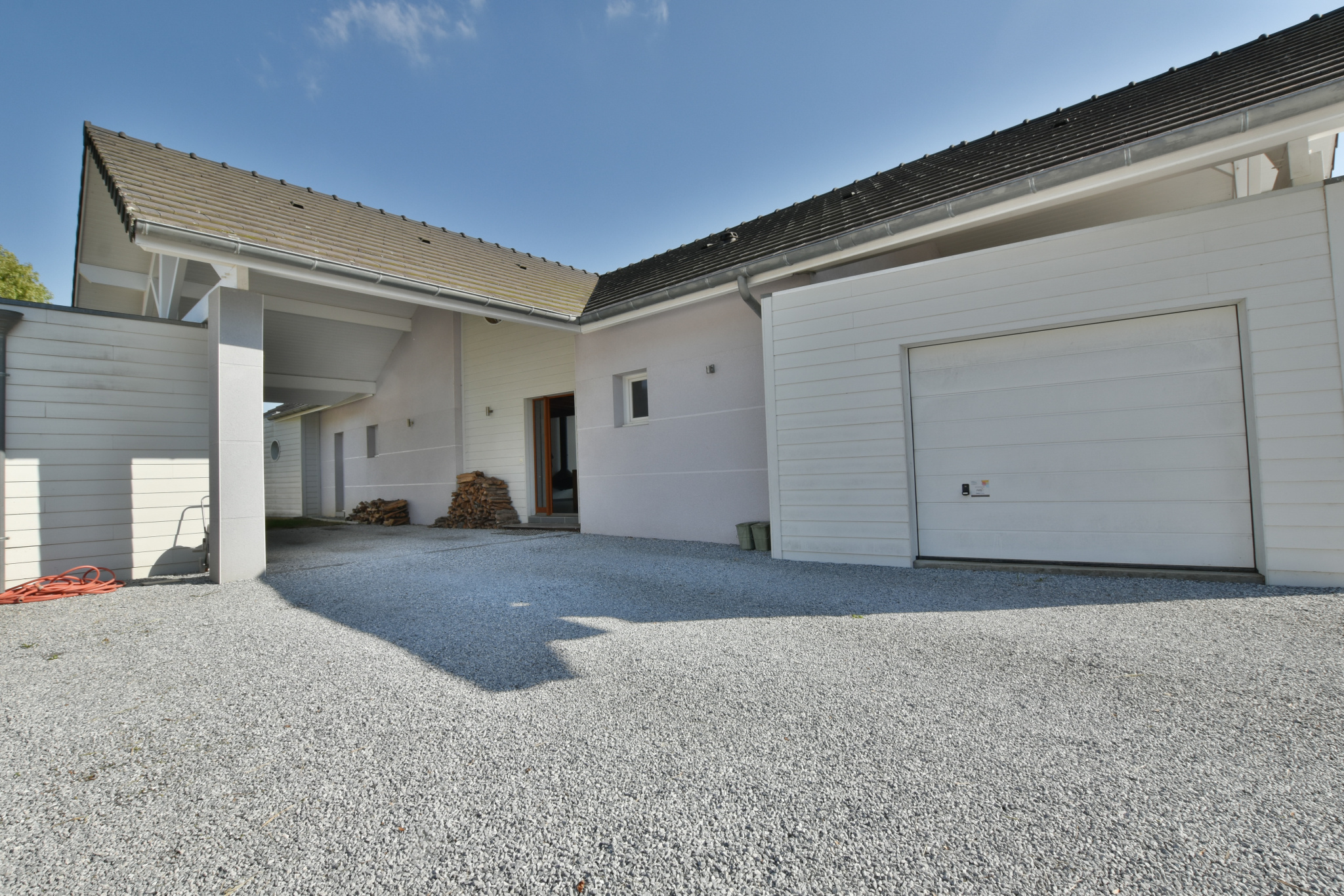 Maison contemporaine à Buros Vue de l'extérieur d'une maison moderne avec garage et allée en gravier.