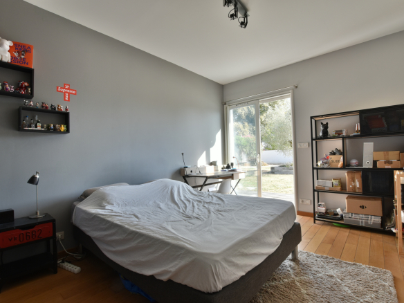 Chambre d'une maison moderne avec un lit, un bureau et une baie vitrée donnant sur l'extérieur.