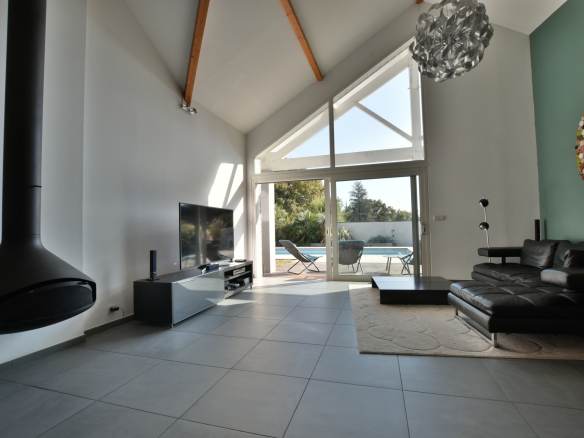 Intérieur moderne d'une maison avec salon spacieux et grandes baies vitrées donnant sur l'extérieur.