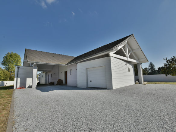 Maison contemporaine avec garage et allée en gravier, entourée de verdure à Buros.