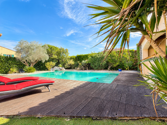 Vue d'une piscine entourée de végétation et de terrasses en bois à Saint-Sériès.