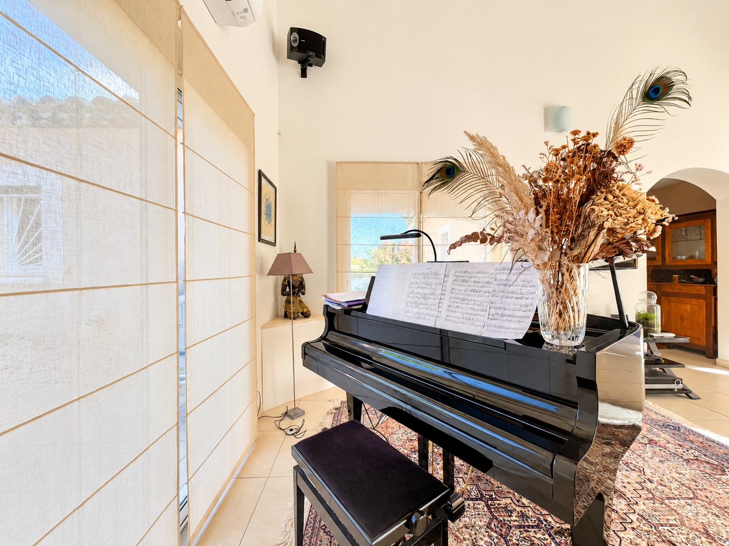 Intérieur d’une maison avec piano Piano noir dans un salon lumineux avec des rideaux et des décorations florales.