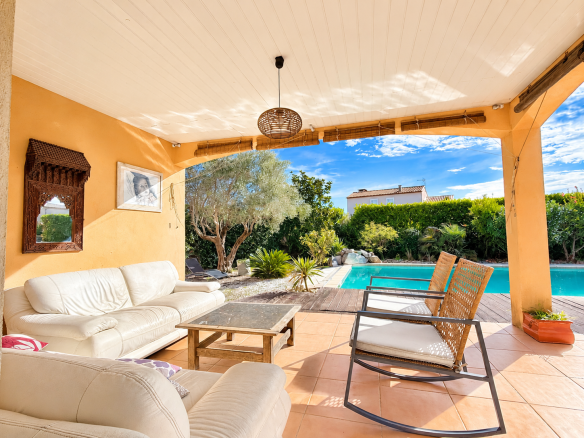 Terrasse d'une maison de plain-pied avec piscine à Saint-Sériès, meubles confortables et jardin.