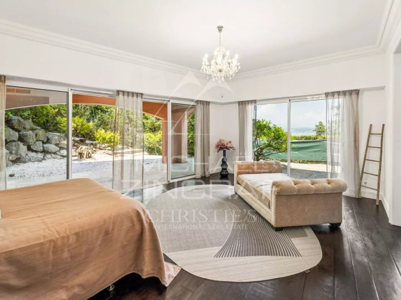 Chambre spacieuse avec vue sur la mer, fenêtres en verre et décoration élégante.