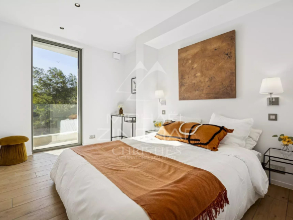 Chambre d'un appartement moderne avec lit double, décoration minimaliste et accès à un balcon.