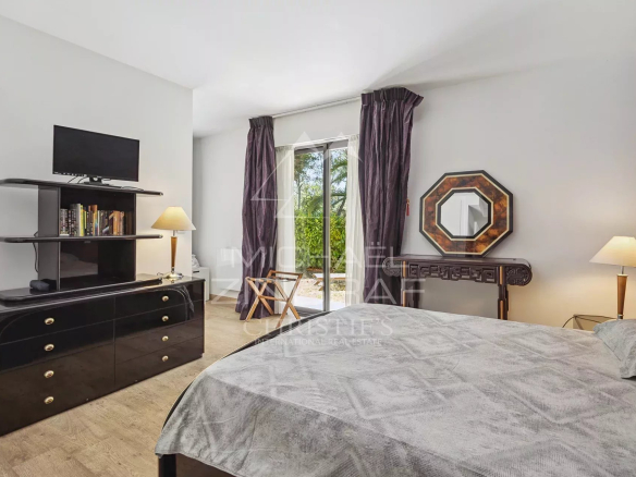 Chambre d'appartement avec lit, télévision et accès à une terrasse à Mandelieu-la-Napoule.