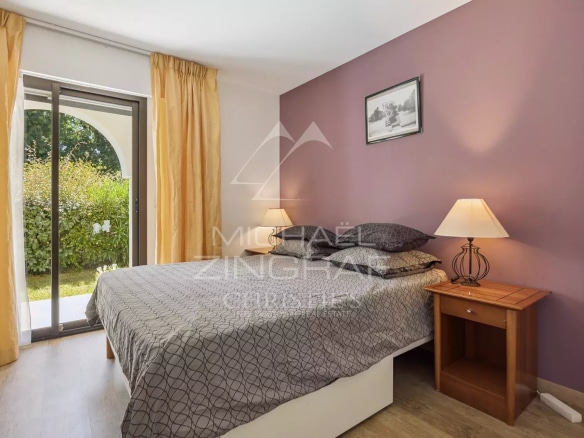 Chambre d'appartement avec lit double et accès à un jardin, murs violets et éclairage doux.