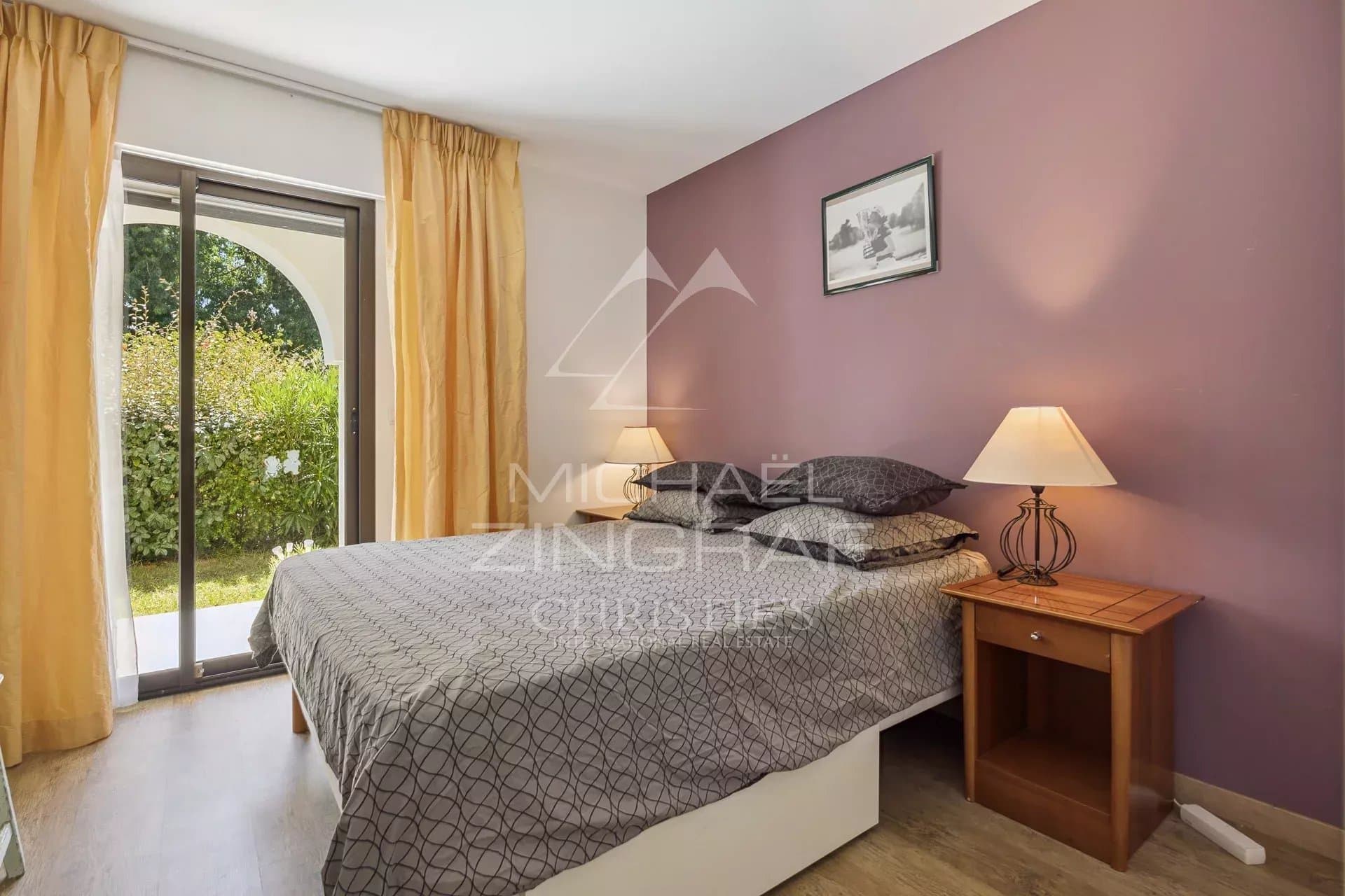 Chambre d’appartement à Mandelieu-la-Napoule Chambre d'appartement avec lit double et accès à un jardin, murs violets et éclairage doux.
