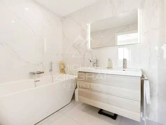 Salle de bain moderne avec baignoire et meuble sous vasque en bois clair.