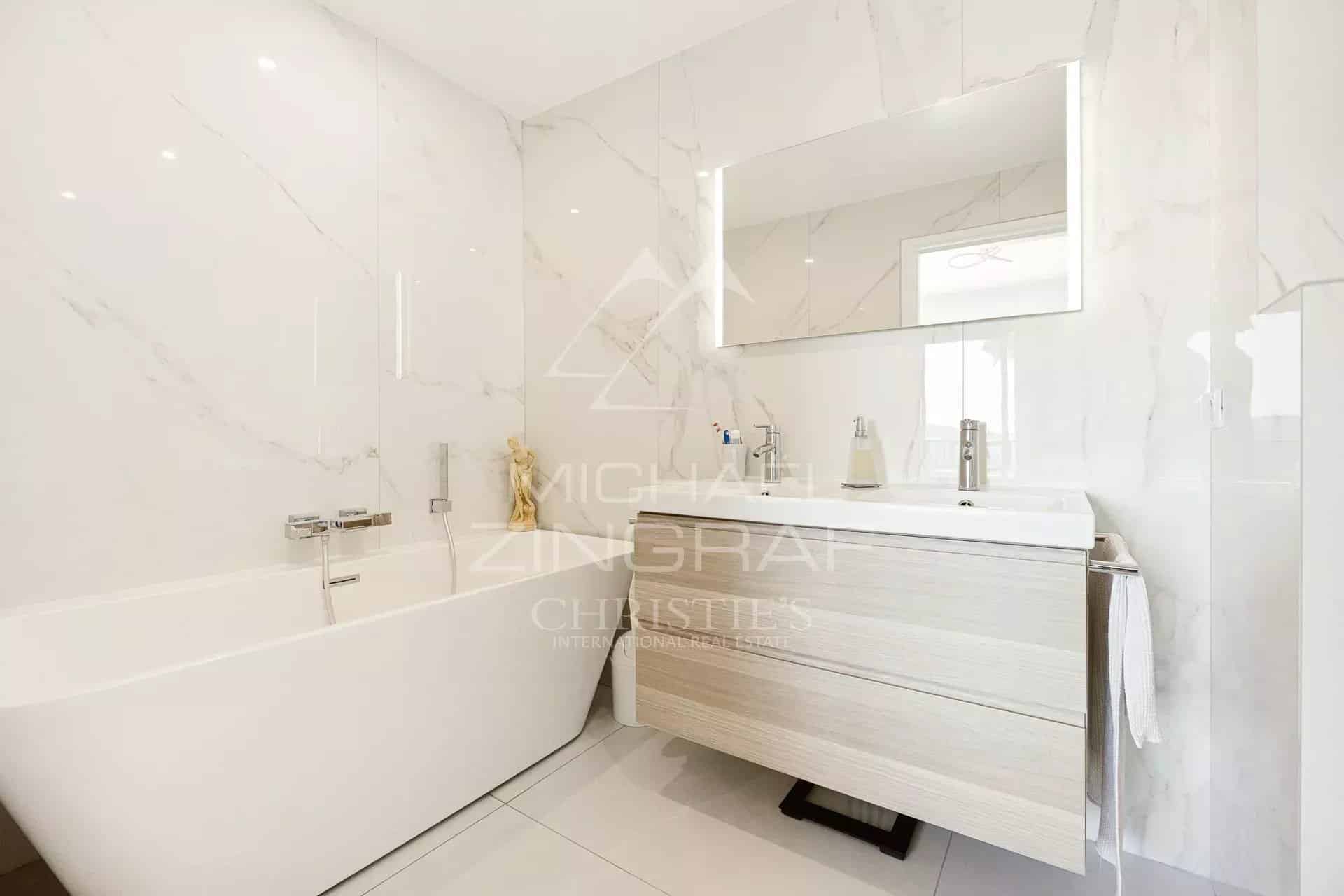 Salle de bain moderne avec baignoire et meuble sous vasque en bois clair.