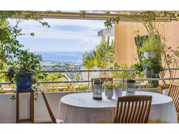 Terrasse d'un appartement avec vue sur la mer et la Baie de Cannes, entourée de verdure.