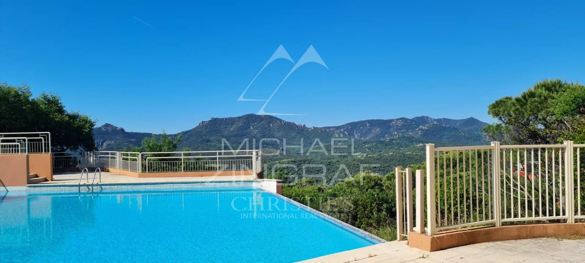 Vue sur la piscine et les collines de l'Estérel depuis un appartement à Mandelieu-la-Napoule.