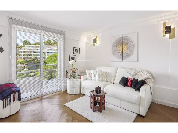 Salon d'un appartement rénové avec canapé blanc et décoration moderne, vue sur la nature.