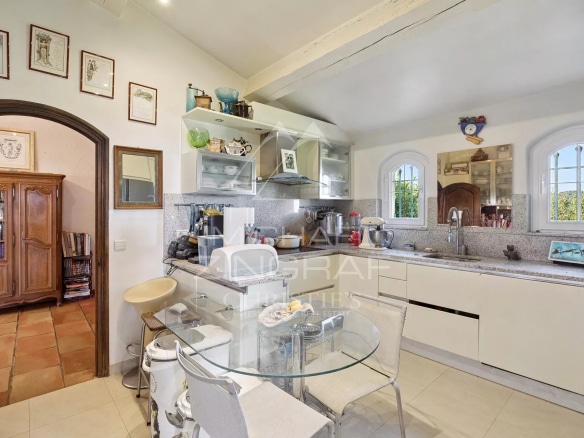 Bright kitchen with modern furniture and dining area, windows offering a view of the outside.
