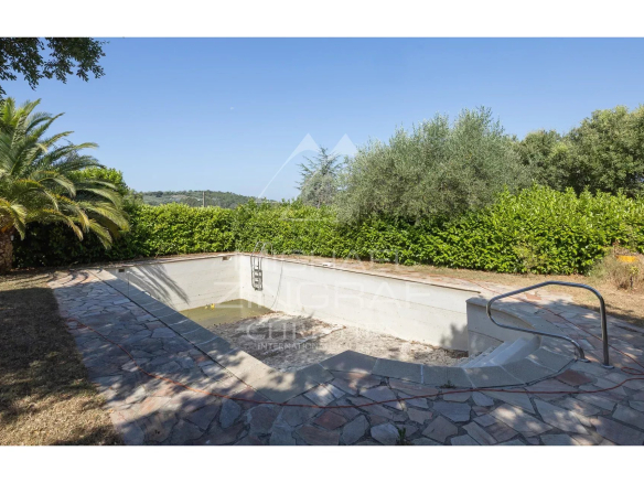 Empty swimming pool surrounded by vegetation on a property in Mandelieu-la-Napoule.