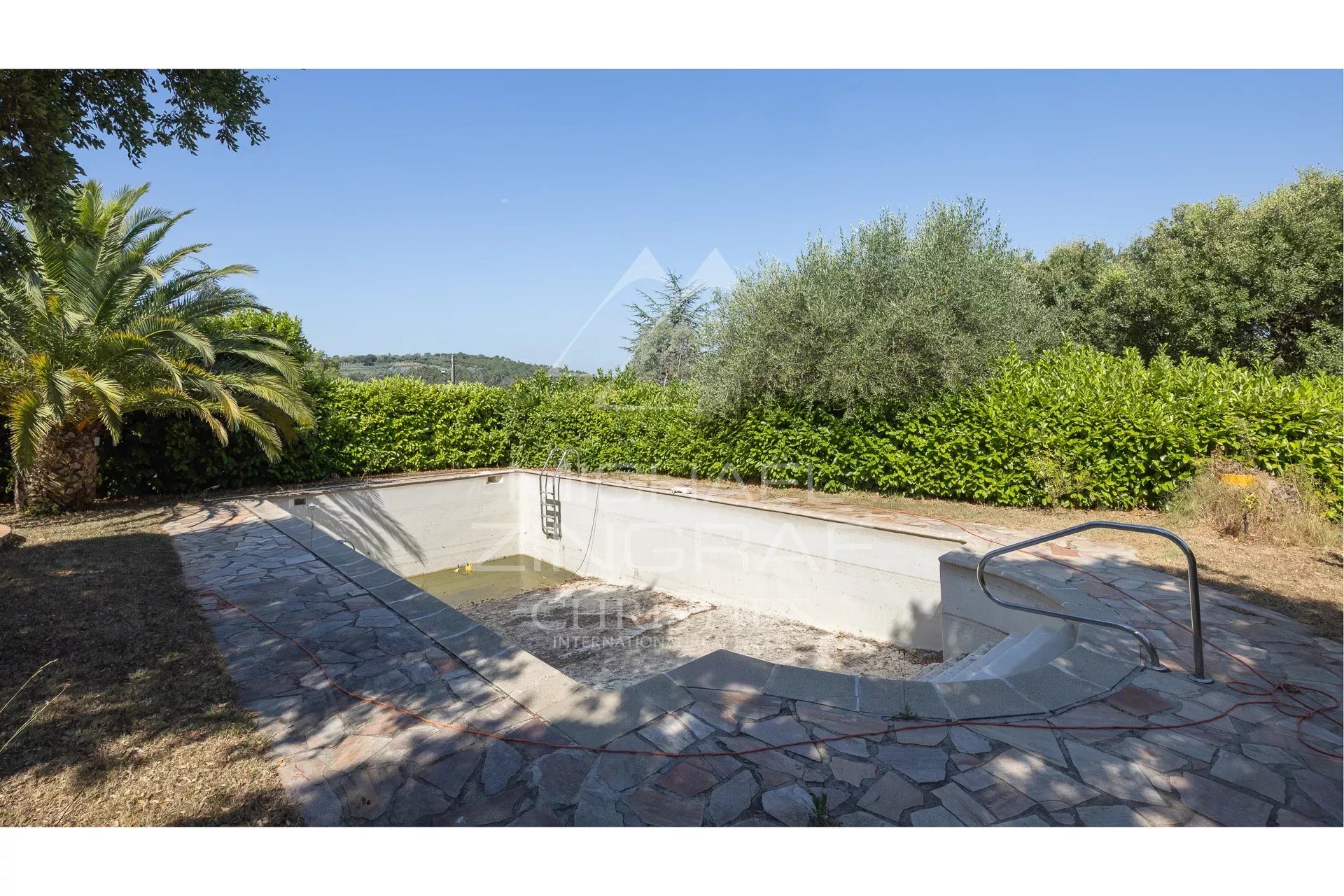 Empty swimming pool surrounded by vegetation on a property in Mandelieu-la-Napoule.